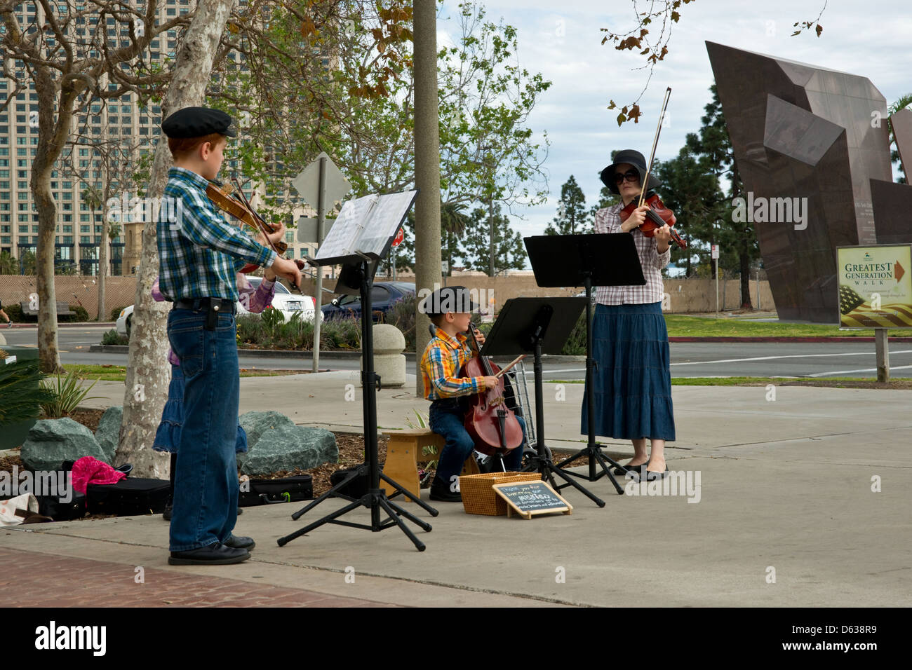 Eine Familie als Straßenmusikant auf der Straße, Violine und Cello zu spielen. Stockfoto