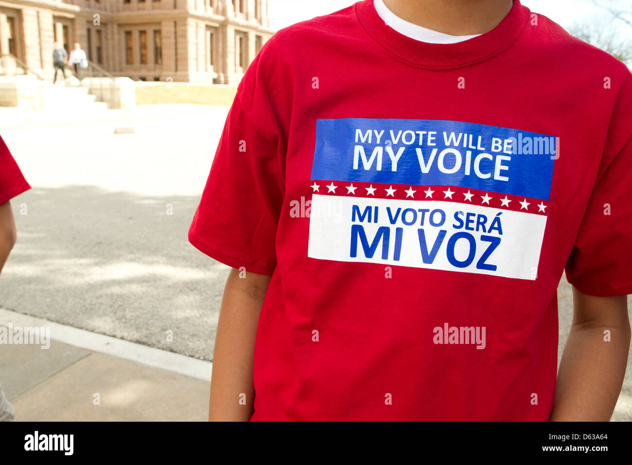 Hispanischer junger Erwachsener trägt T-shirt mit zweisprachigen Nachricht in Englisch und Spanisch sating seine Stimme in seiner Stimme Stockfoto