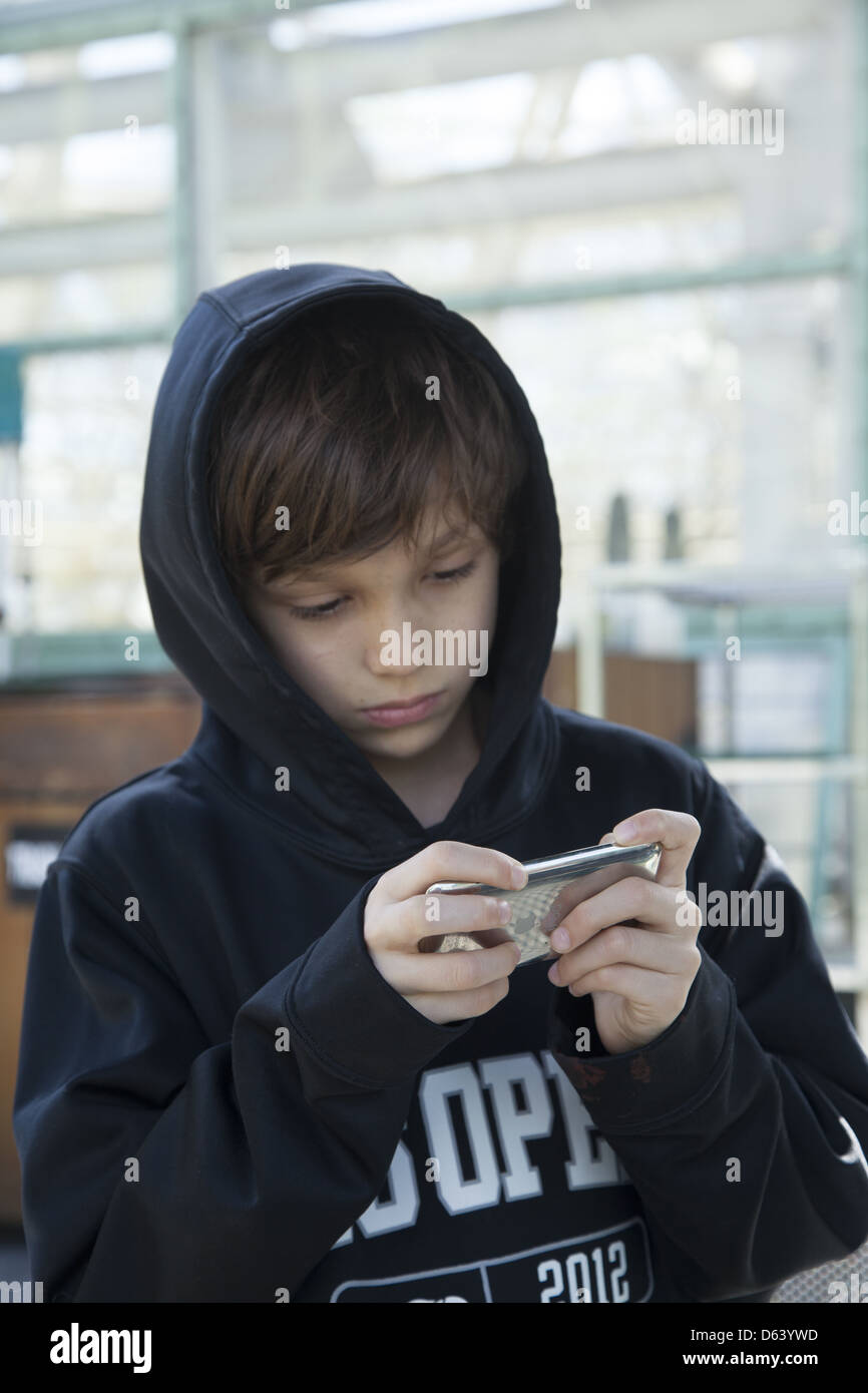 9 Jahre alter Junge spielt Minecraft auf seinem iphone. Stockfoto