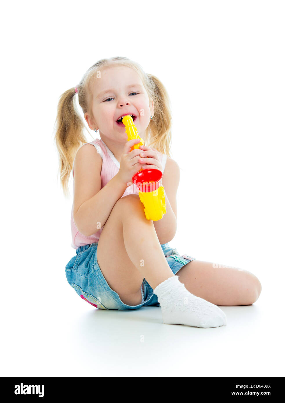 Lustige Babymädchen spielen mit Spieluhr. Isoliert auf weißem Hintergrund Stockfoto