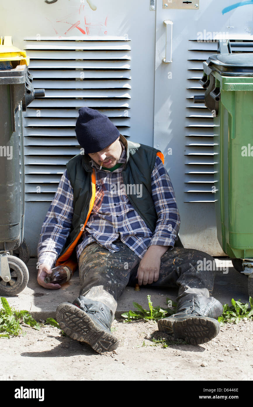Tramp schlafen in der Nähe von Mülltonnen Stockfoto