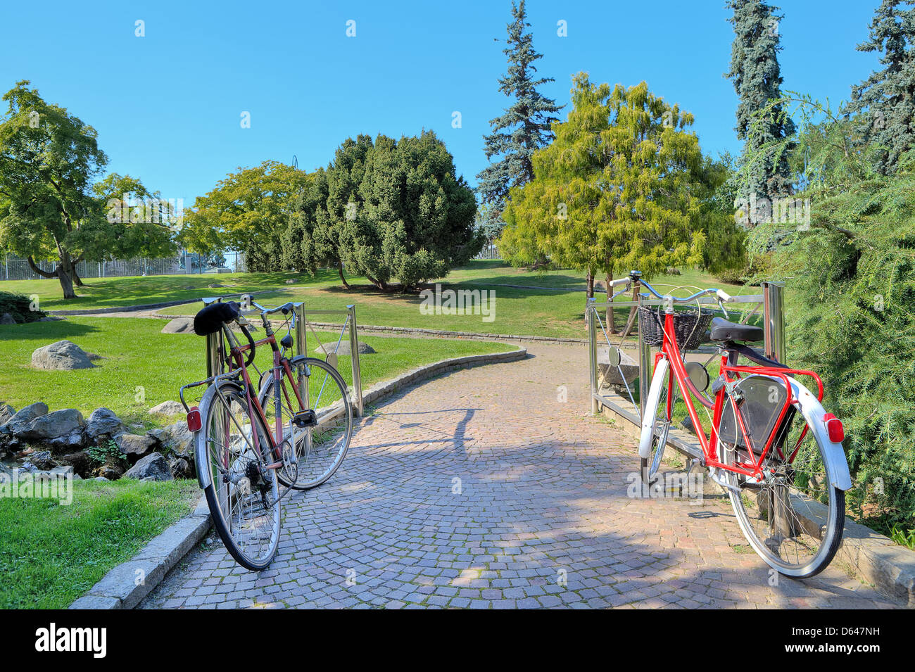 Zwei Fahrräder steht auf schmalen gepflasterten Gehweg zwischen grünen Wiesen und Bäumen auf botanische Teil der Valentino-Park in Turin, Italien. Stockfoto