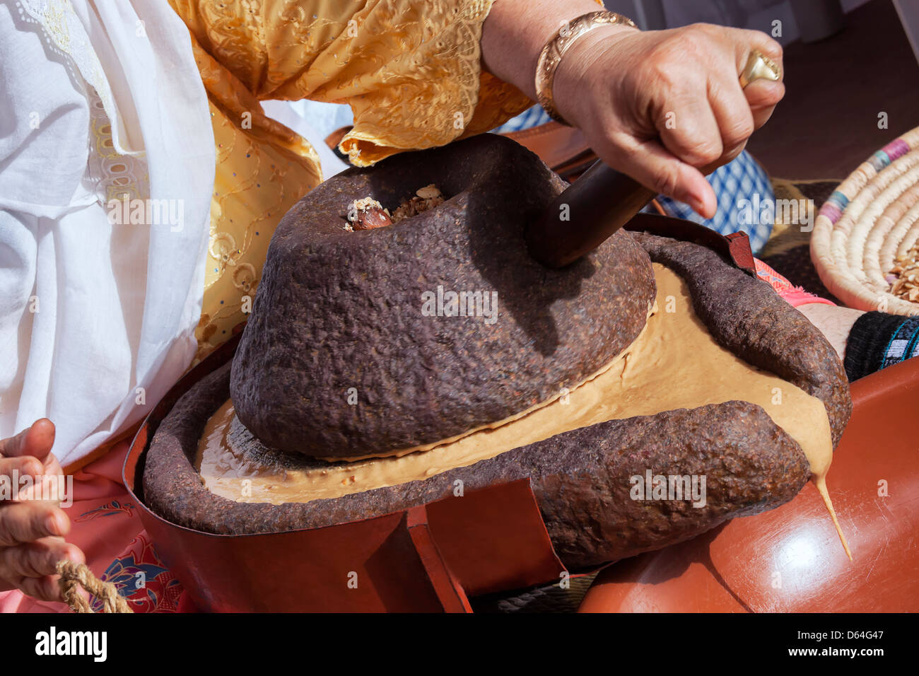 Marokkanerin Schleifen Argan Kernel traditionell mit einem Mühlstein. Stockfoto