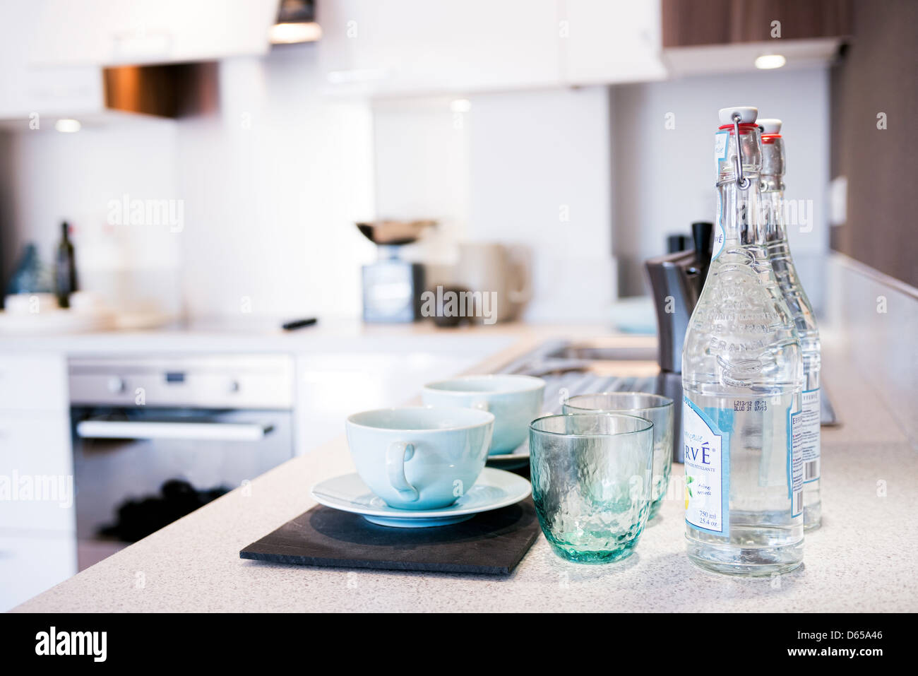 Sorgfältig angelegt, Tassen, Untertassen, Gläser und Flaschen mit Wasser in eine moderne Küche Stockfoto