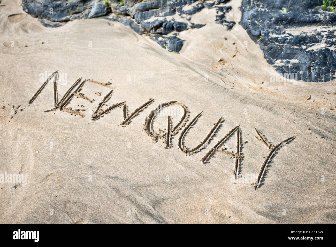 Das Wort Newquay geschrieben im Sand am Strand Stockfoto