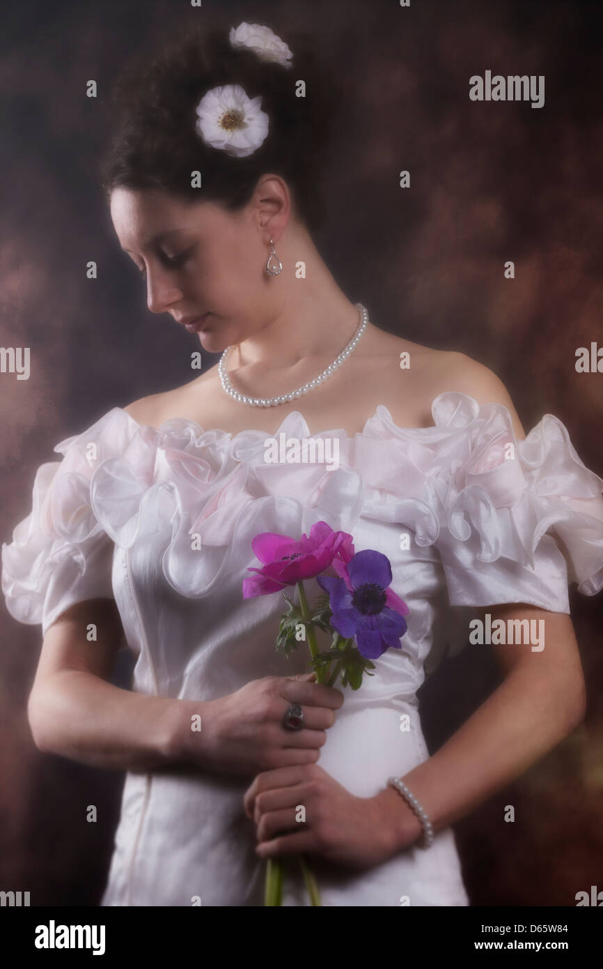 schöne Frau in einem weißen Kleid mit lila Blüten Stockfoto