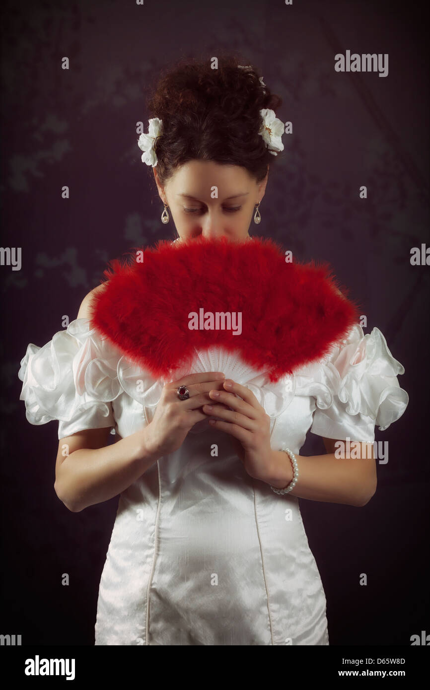 eine Frau in einem weißen Kleid mit einem roten Ventilator Stockfoto
