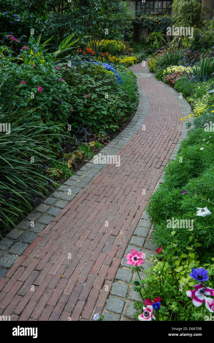 Ziegelsteinweg durch Blumengarten Stockfoto