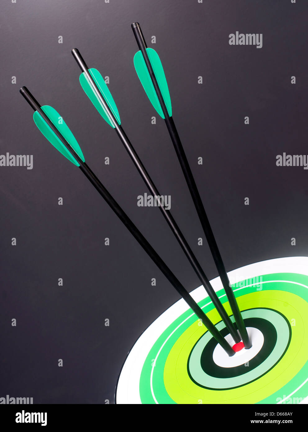 Drei grüne und schwarze Bogenschießen Pfeile Hit Runde Multi farbige Ziel Bullseye Center Stockfoto