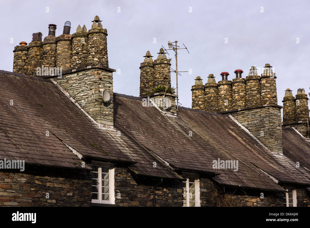 Schieferschornsteine, quadratische Schornsteine und runde Töpfe über terrassenförmig angelegten Lageland Cottage Dächern, Skelwith, Cumbria, England, Großbritannien Stockfoto
