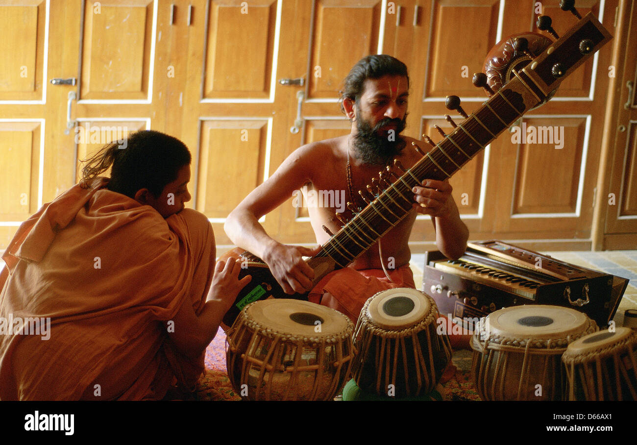 Ein hinduistischer Mönch ("Sadhu") spielt Sitar, während ein Neuling hört. Beide gehören der Swaminarayan-Sekte (Indien) Stockfoto