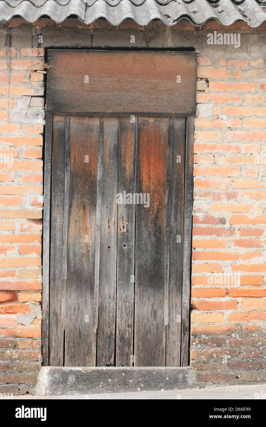 Eine verwitterte braune Tür in eine Wand aus Lehmziegeln in Cotacachi, Ecuador Stockfoto
