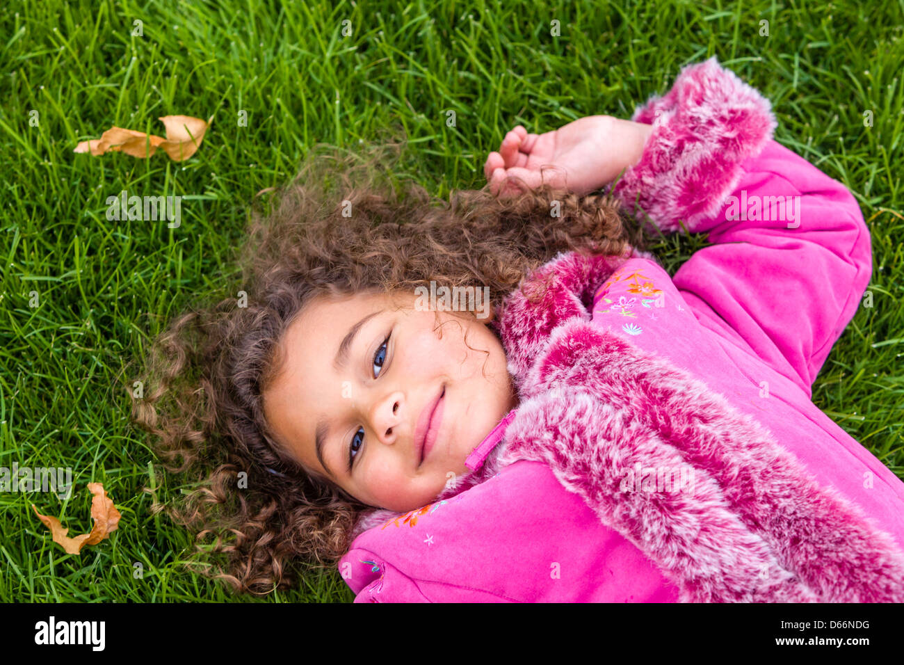Junges Mädchen im Rosa liegen auf dem Rasen. Stockfoto