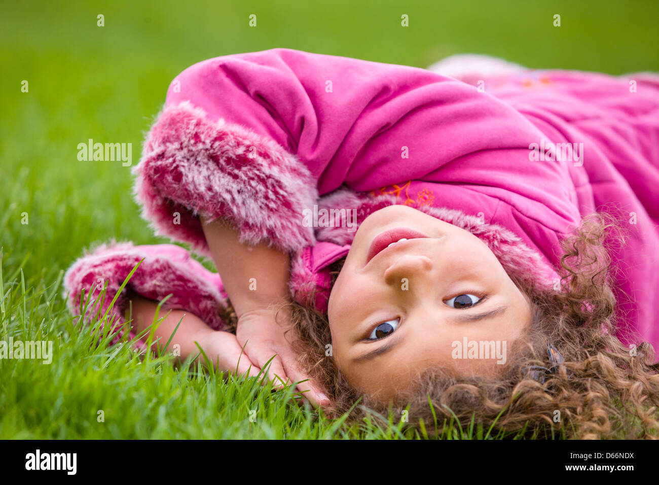 Junges Mädchen im Rosa liegen auf dem Rasen. Stockfoto