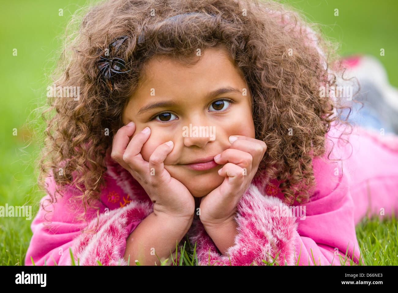 Junges Mädchen auf dem Gras liegend mit den Händen auf ihrem Gesicht. Stockfoto