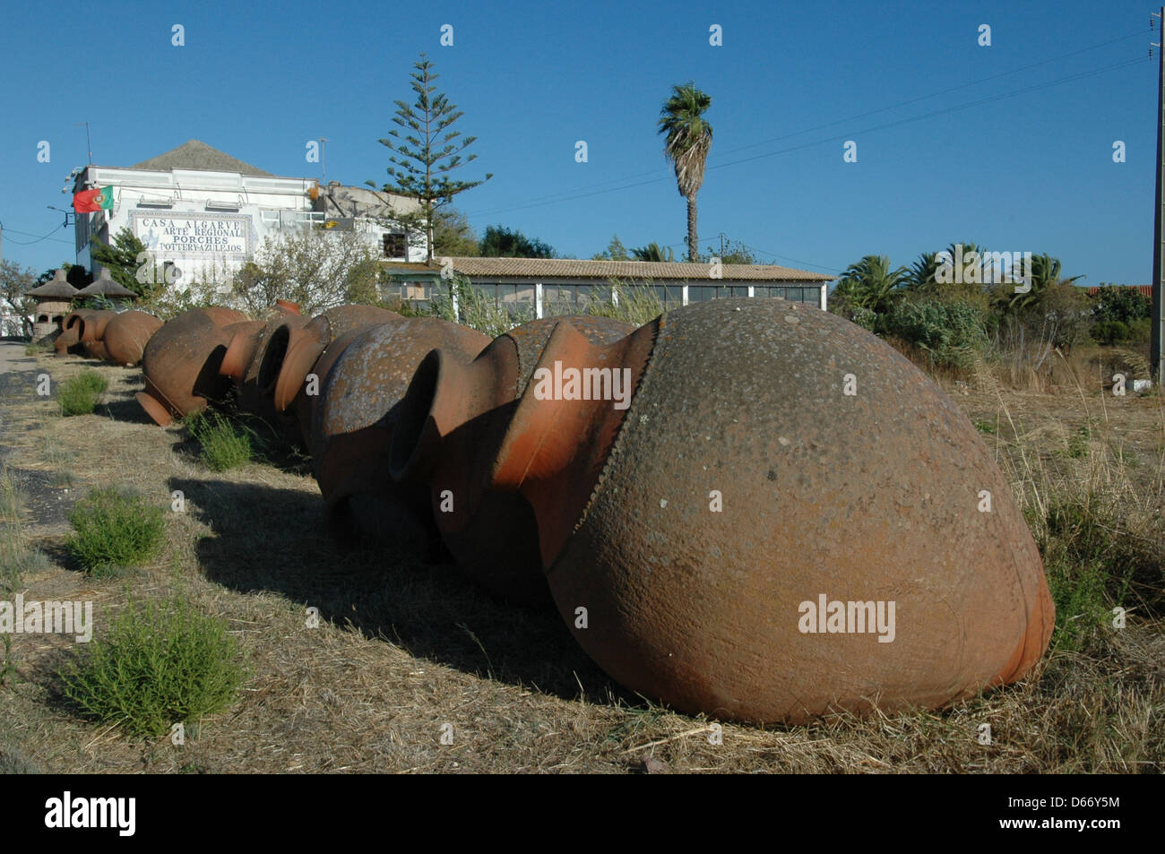 Große Terrakotta-Gefäße, die traditionellen Töpfergefäßen ähneln, wie z. B. Tinajas oder kvevri, die zur Lagerung von Wein oder Öl verwendet werden, die vor einer Töpferei in der Algarve, der südlichsten Region Portugals, ausgestellt werden. Stockfoto
