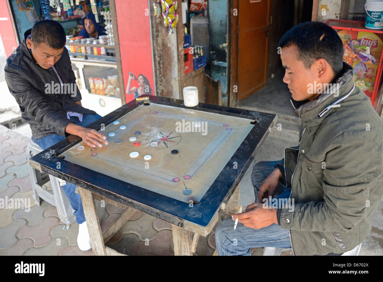 Ein paar tibetischen Jugendlichen spielen einer tibetische Brettspiel n Majnu Ka Tila tibetische Flüchtlingslager in Delhi, Indien Stockfoto