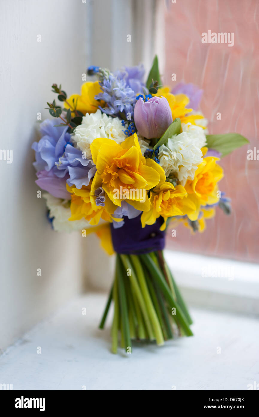 Brautstrauß von Frühlingsblumen wie Tulpe, Narzisse, Sweet Pea in gelb, blau, Pink und lila durch ein Fenster Stockfoto