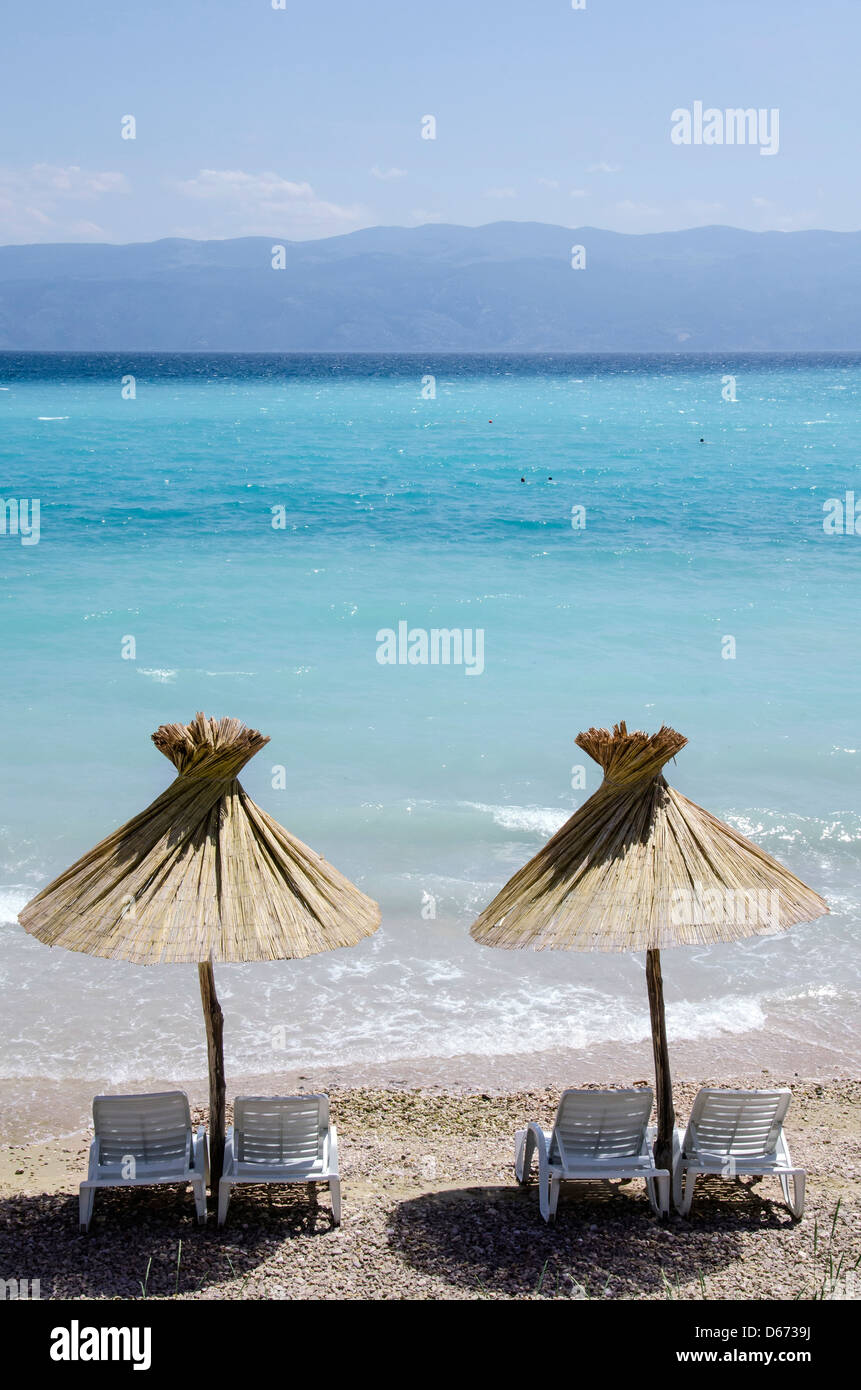 Sonnenliegen mit Reedumbrella am Strand. Meer und Strand. Stockfoto