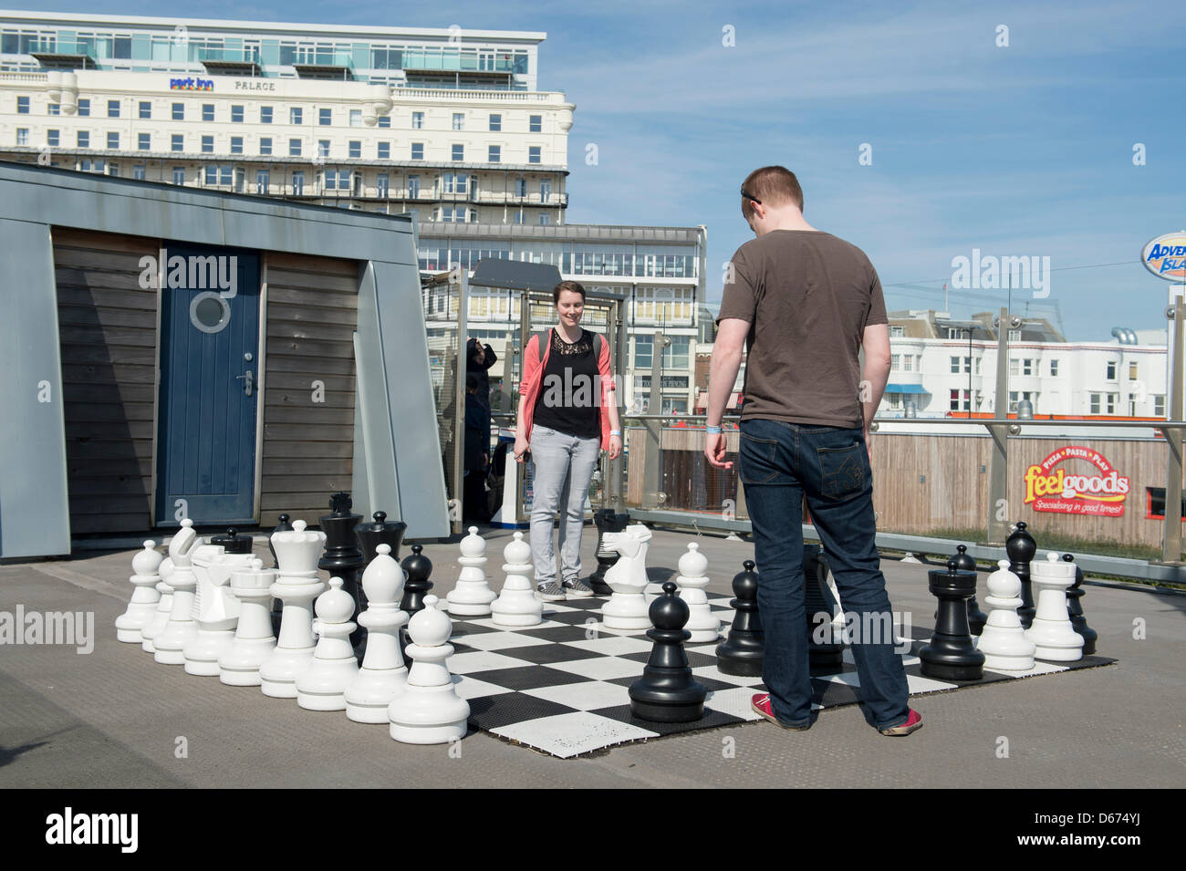 Ein junges Paar genießen das gute Wetter, da sie über große Schach zu Beginn des Southend Pier, in Essex, England spielen. Stockfoto