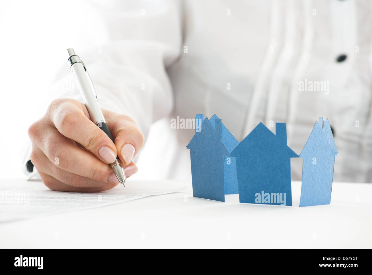 Ausfüllen des Formulars mit Papier Hand Häuser im Vordergrund. Stockfoto