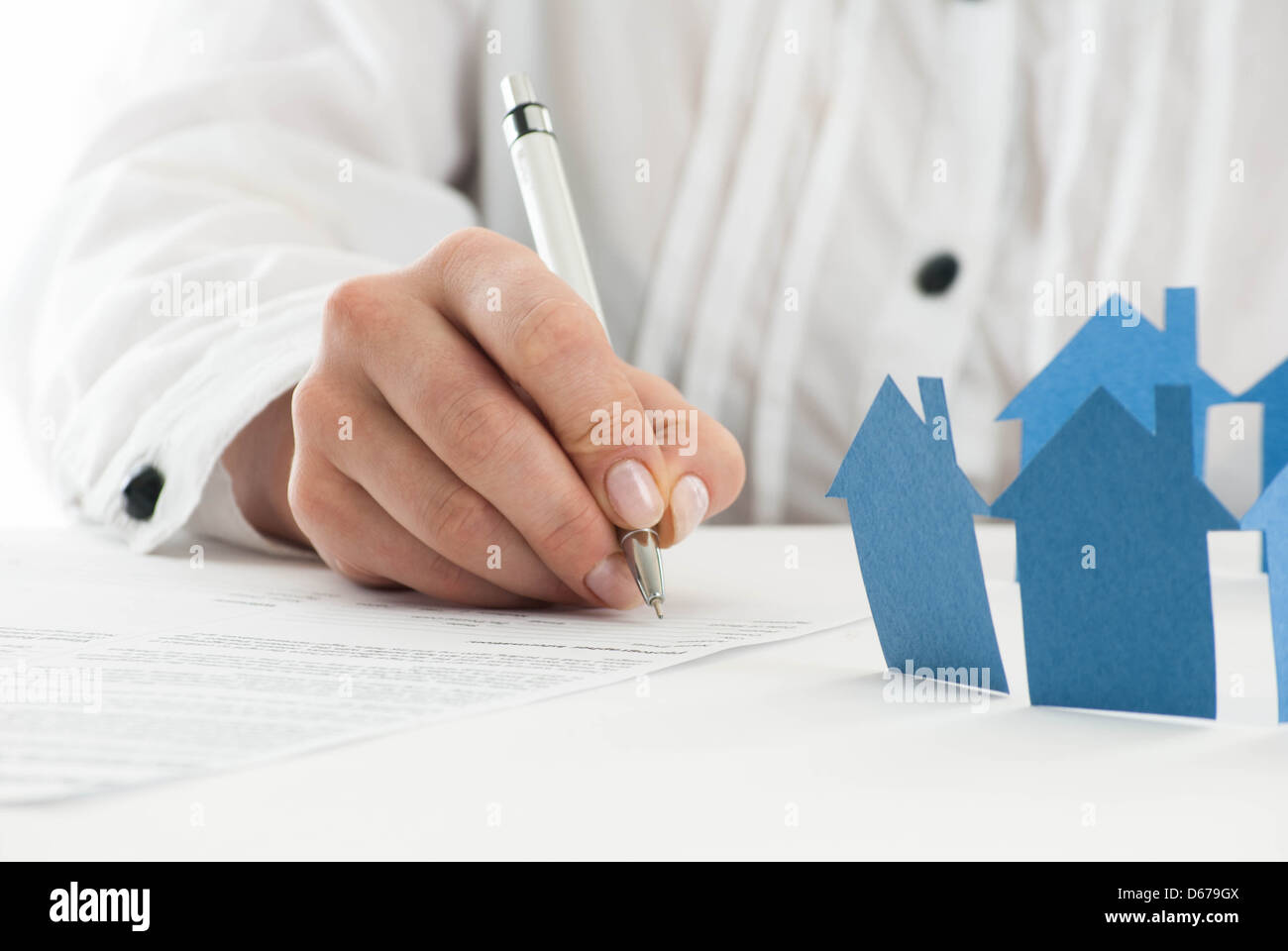 Ausfüllen des Formulars mit Papier Hand Häuser im Vordergrund. Stockfoto