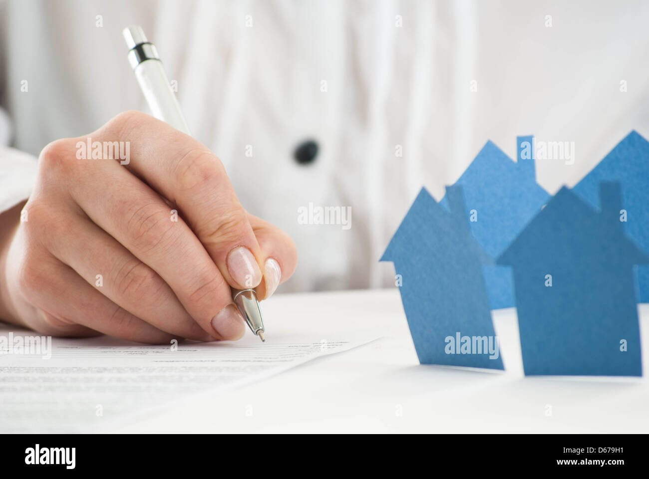 Ausfüllen des Formulars mit Papier Hand Häuser im Vordergrund. Stockfoto