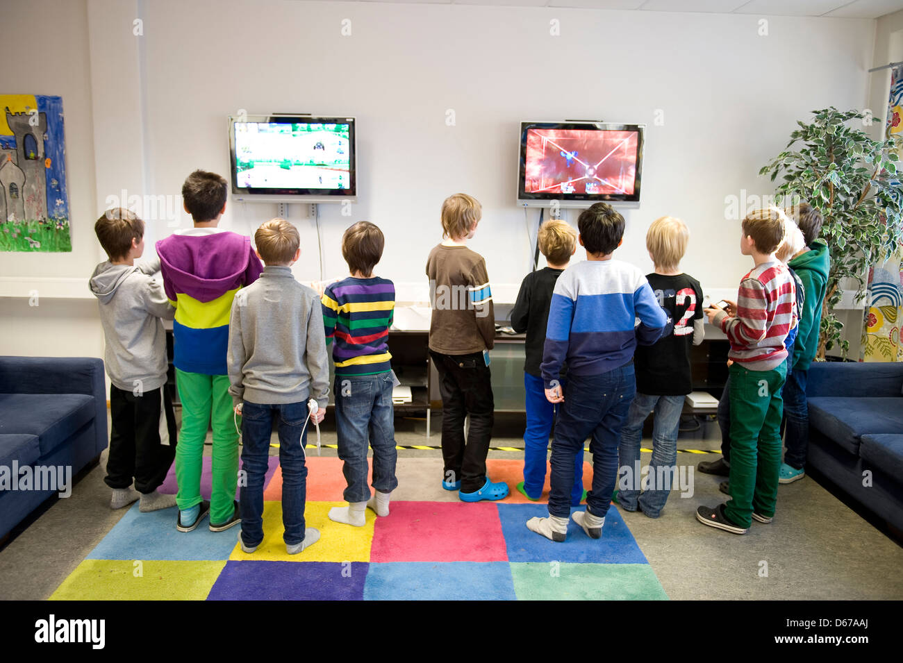 Eine Gruppe von jungen im Alter zwischen 7 und 10 Video abspielen und Internet-Spiele auf zwei Bildschirmen an der Wand. Stockfoto