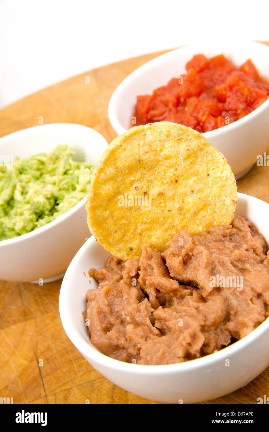 Essen Vorspeisen Chips und Salsa Bohnenmus Guacamole auf Holz Schneidebrett Stockfoto