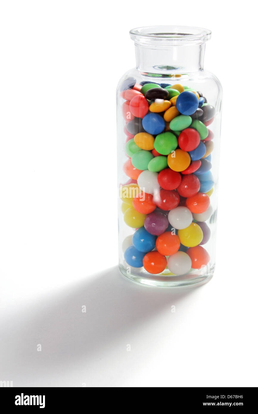 Glasflasche mit Schokolinsen Stockfoto