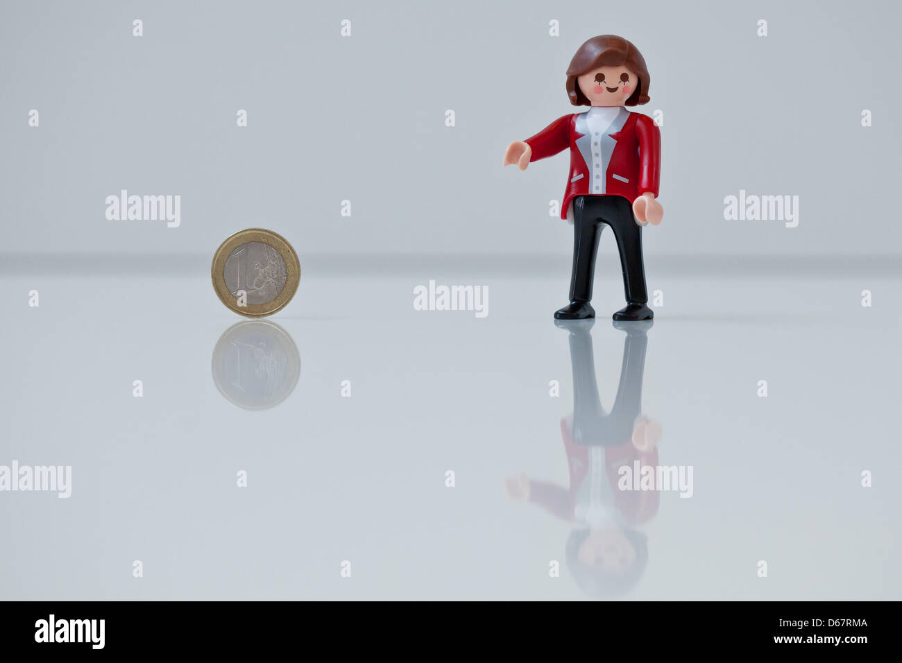 Eine Abbildung zeigt Bundeskanzlerin Angela Merkel als Playmobil-Figur hält eine Euro-Münze auf der Spielzeughersteller Playmobil in Zirndorf, Deutschland, 28. Juni 2012. Die Figur war ein Geschenk für die deutsche Bundeskanzlerin und werden nicht verkauft. Heute treffen sich die europäischen Staats-und Regierungschefs auf dem zweitägigen EU Gipfel in Brüssel. Foto: Daniel Karmann Stockfoto