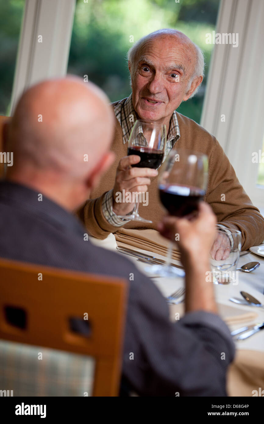 Älterer Mann mit einer Mahlzeit mit einem Freund. Chatten, glücklich und amüsiert sich. Stockfoto