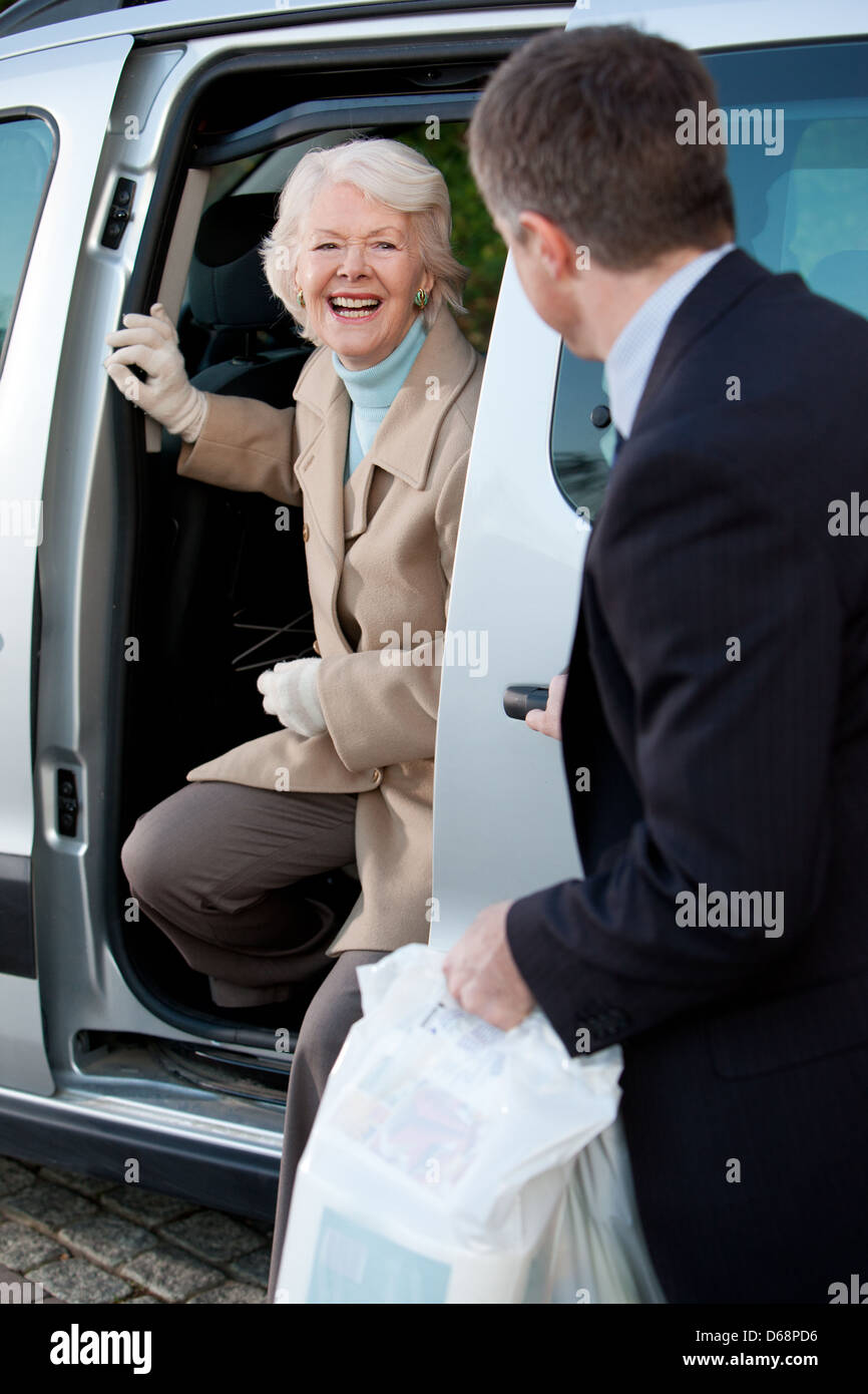 Ältere Frau, die immer aus einem Taxi mit Hilfe eines Chauffeurs. Stockfoto