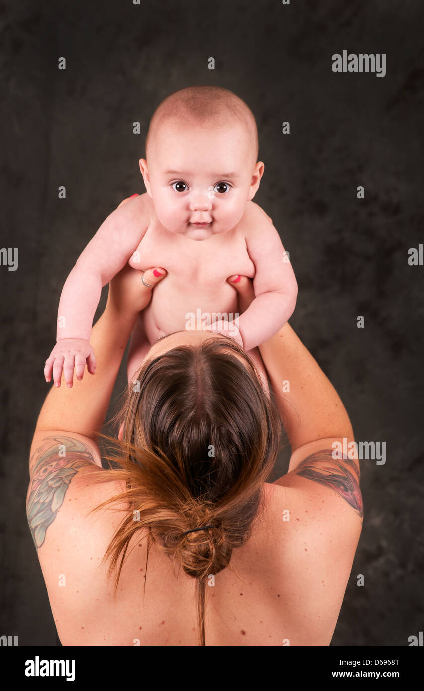 Schöne Mutter hält ihr Baby mit tattoos Stockfoto