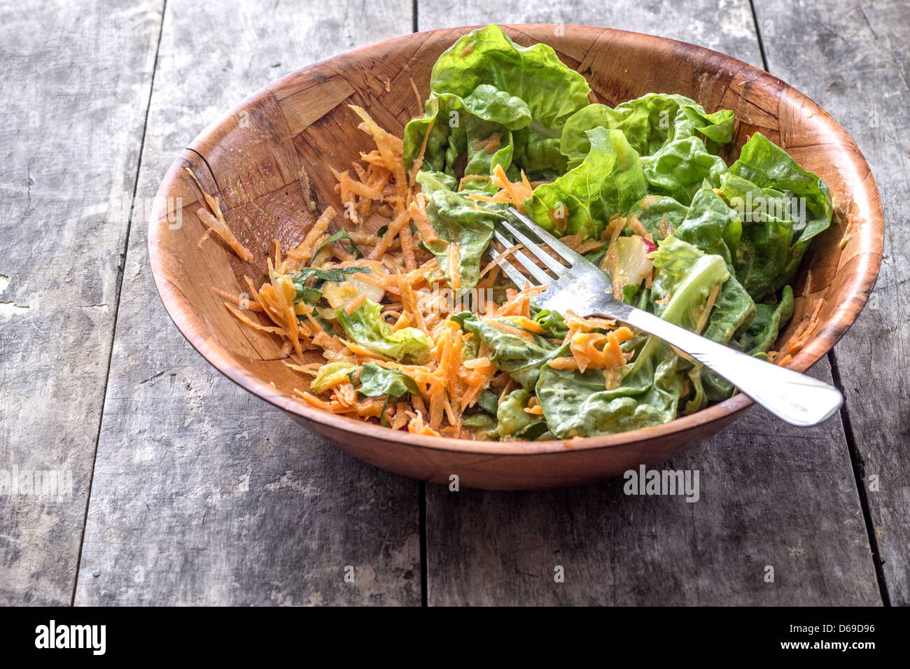 Grüner Salat mit geriebenen Möhren auf Tisch, halb leer Stockfoto