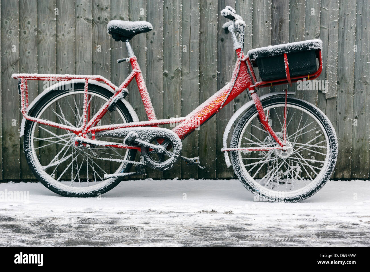 Königliche Post post Lieferung Fahrrad lehnt sich gegen einen Holzzaun nach Winterstürmen Großbritannien getroffen. Stockfoto