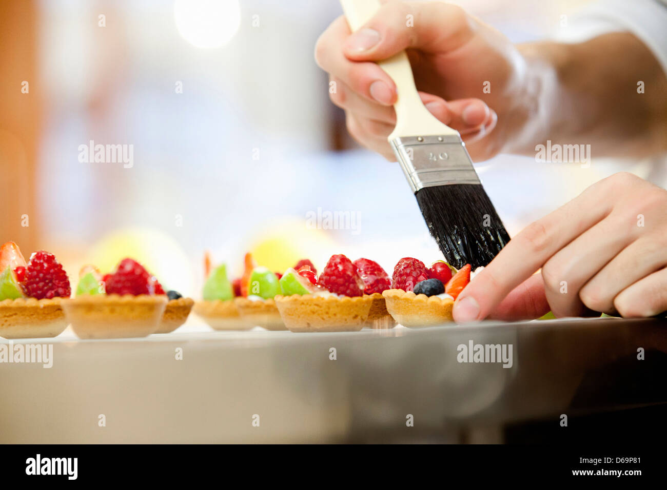 Baker Verglasung Obstkuchen in Küche Stockfoto