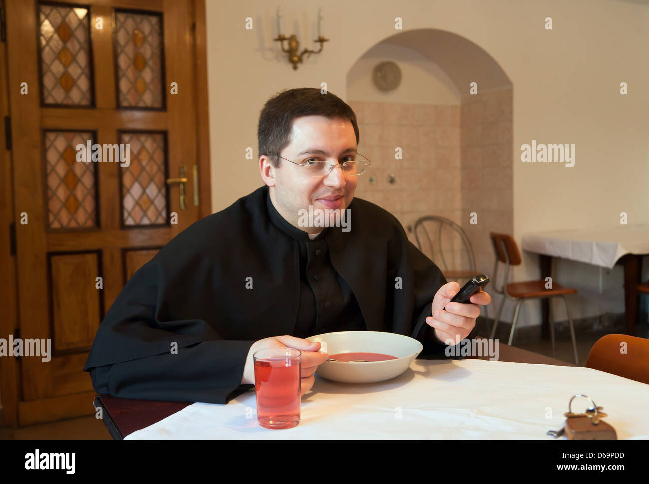 Krakau, Polen, Priester untersucht den Text von seinem Handy beim Essen Stockfoto