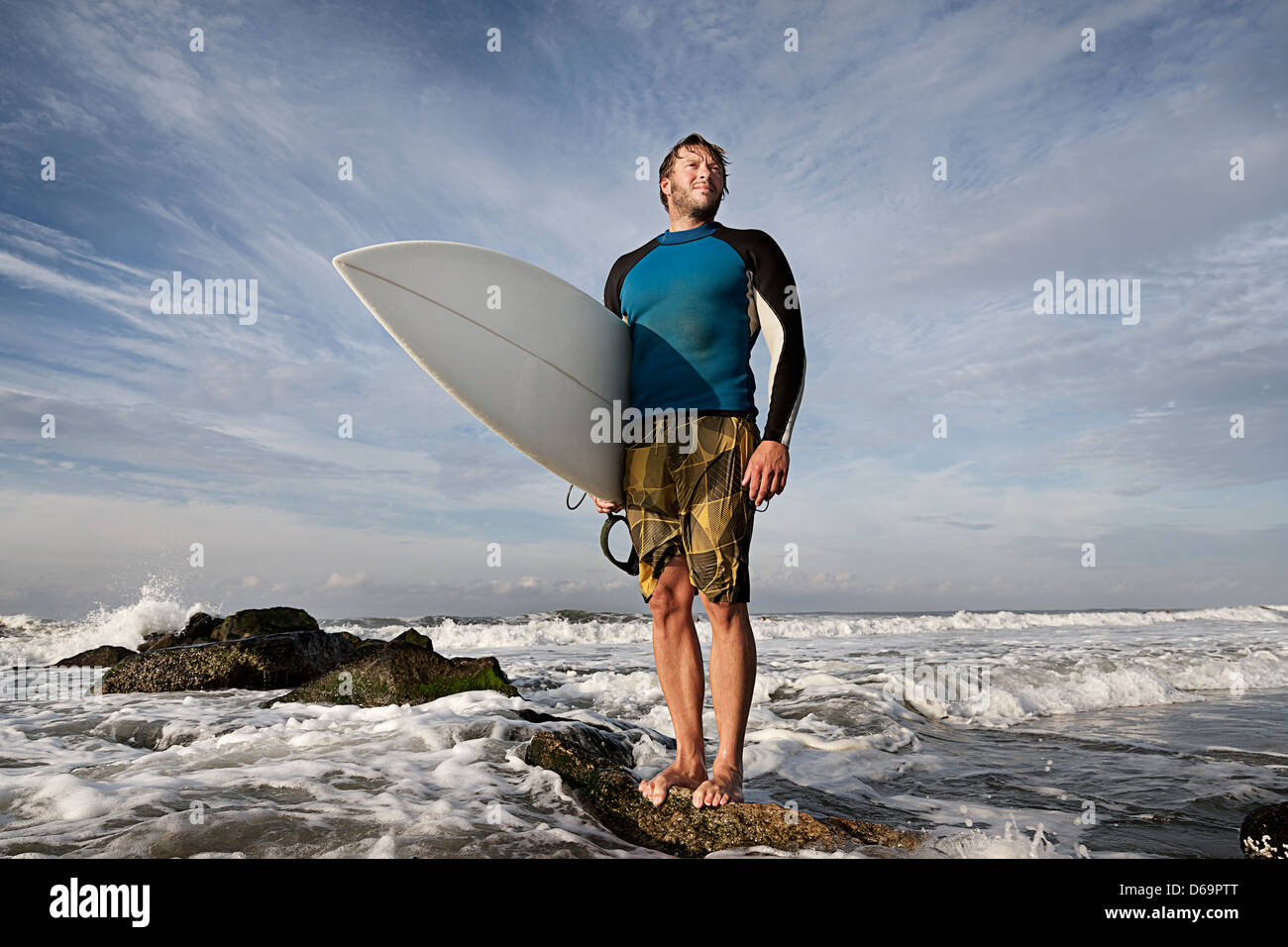 Surfer, die auf Felsen am Strand Stockfoto