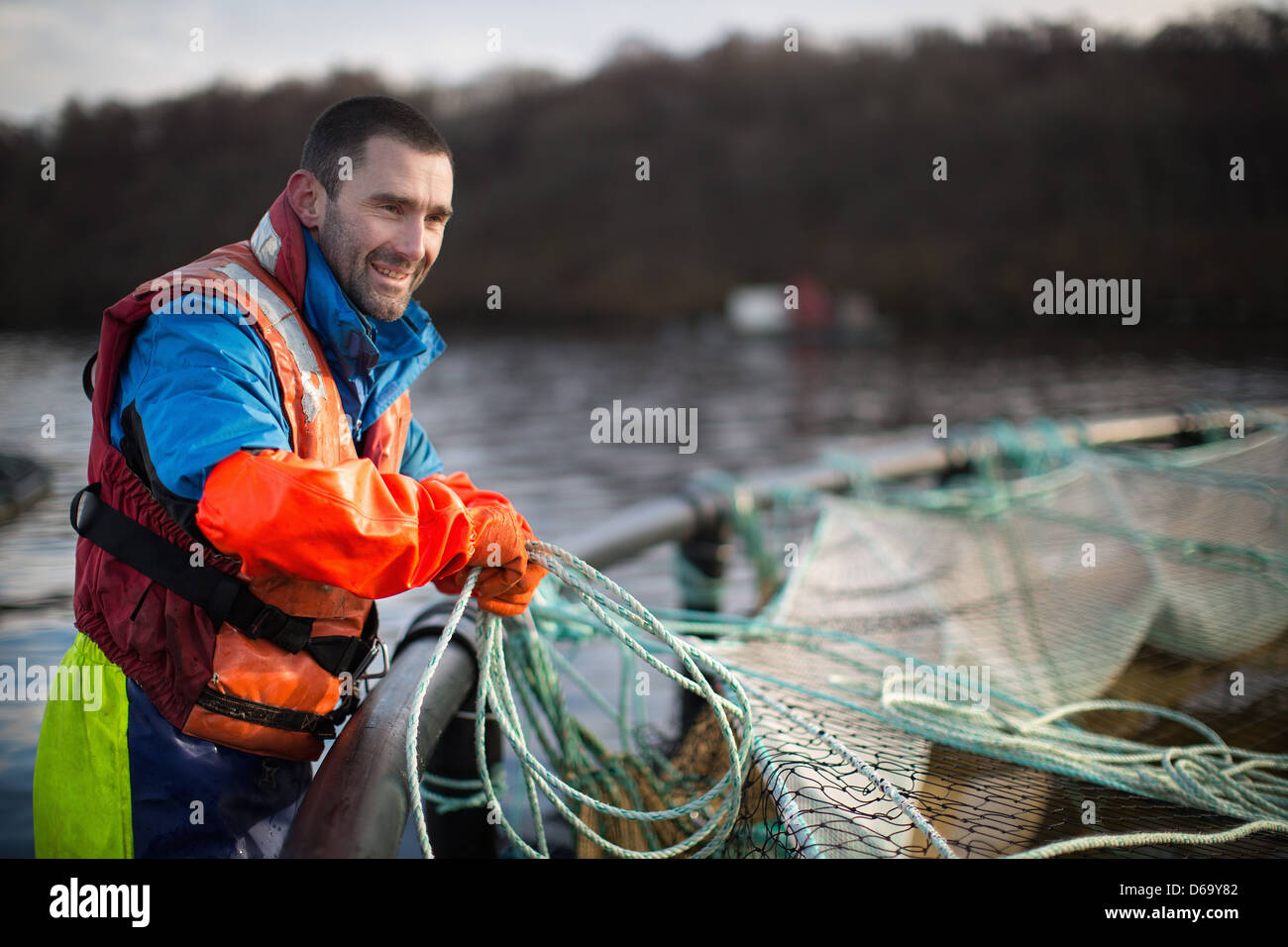 Worker bei Lachsfarm im ländlichen See Stockfoto