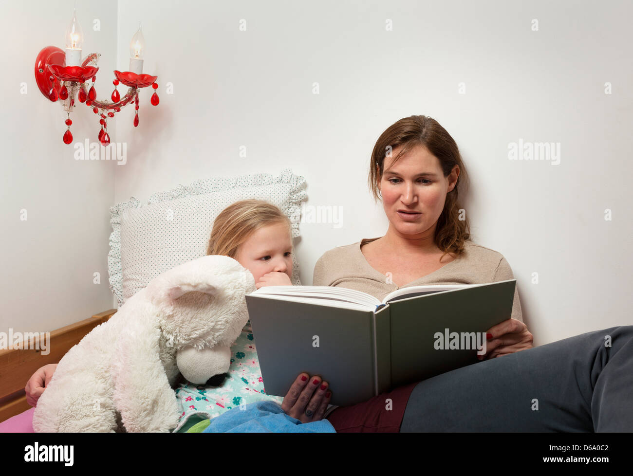 Mutter Tochter im Bett lesen Stockfoto