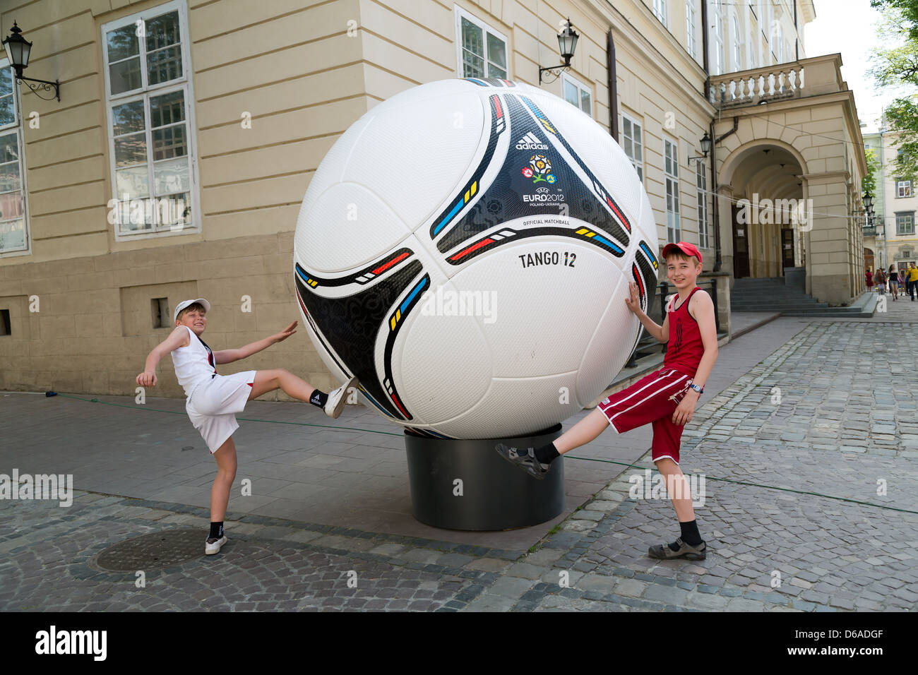 Lviv, Ukraine, Jungs posieren gegen eine überdimensionale Modell des Adidas Tango 12 Stockfoto