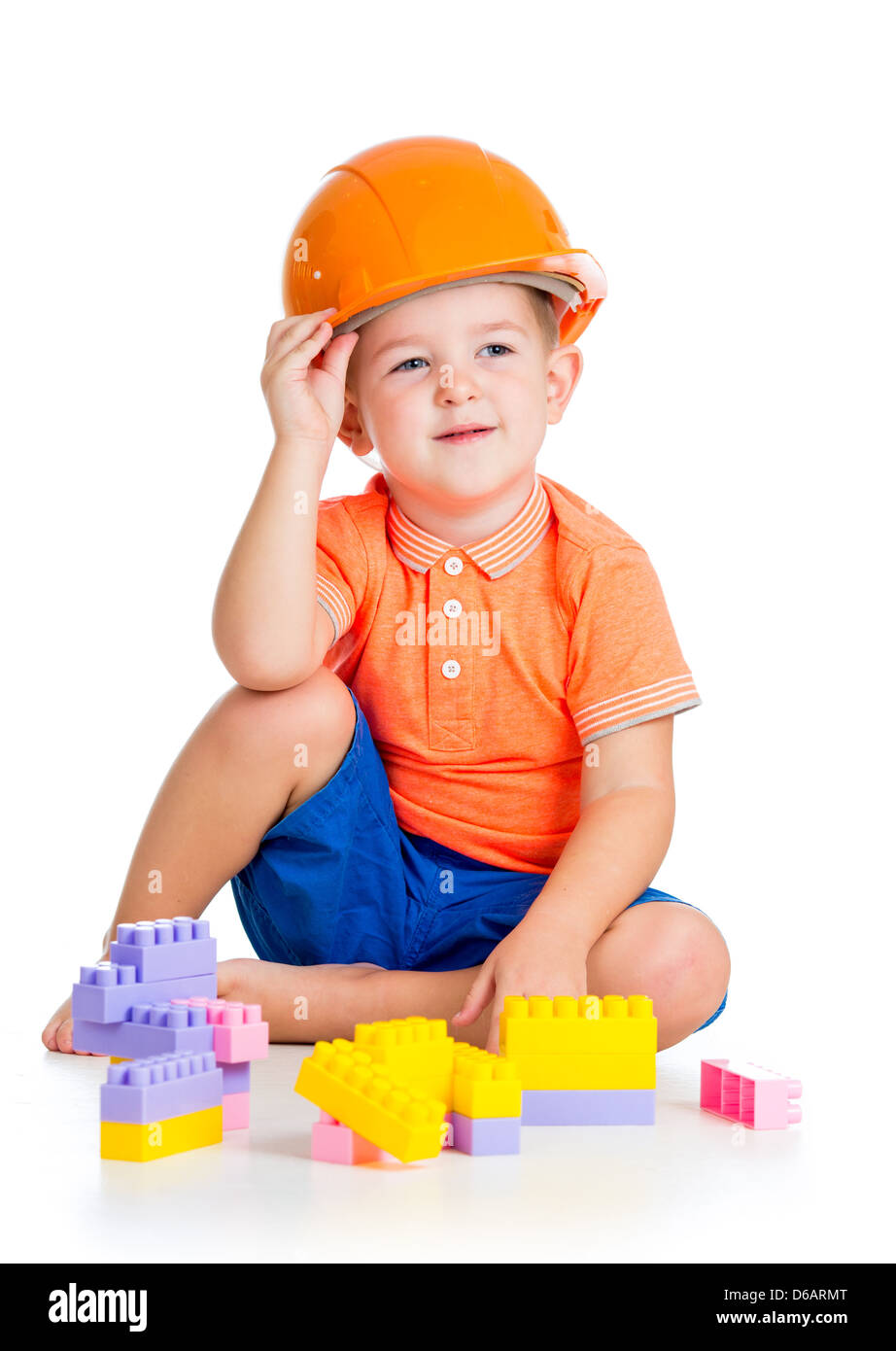 fröhliches Kind Junge mit Schutzhelm spielen mit Bausteine-Spielzeug auf weißem Hintergrund Stockfoto