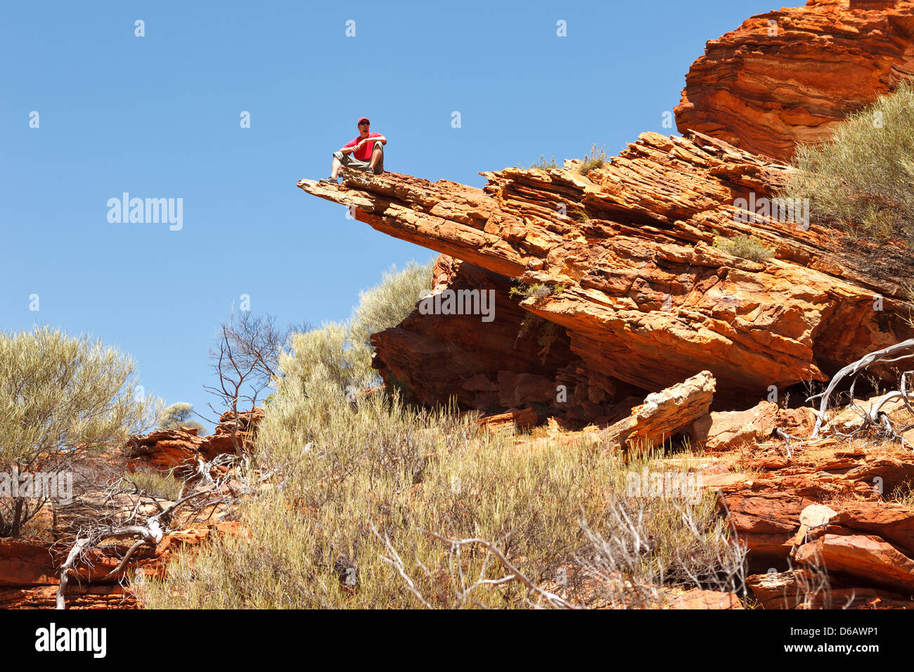 Mann sitzt auf der Felskante, Schleife zu Fuß, Kalbarri Nationalpark, Western Australia Stockfoto