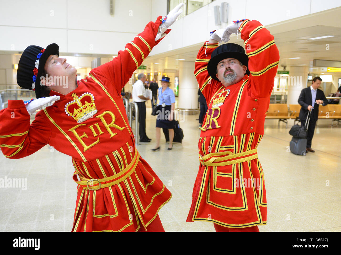 Zwei Schauspieler, verkleidet als königliche Beefeaters, posieren mit den Gesten von London 2012 Olympische Spiele, das Blitzsymbol Usain Bolt (L) und M Mo Farah, um Reisende am Flughafen Heathrow, London, Großbritannien, 13. August 2012 zu unterhalten. Foto: Jochen Luebke Stockfoto