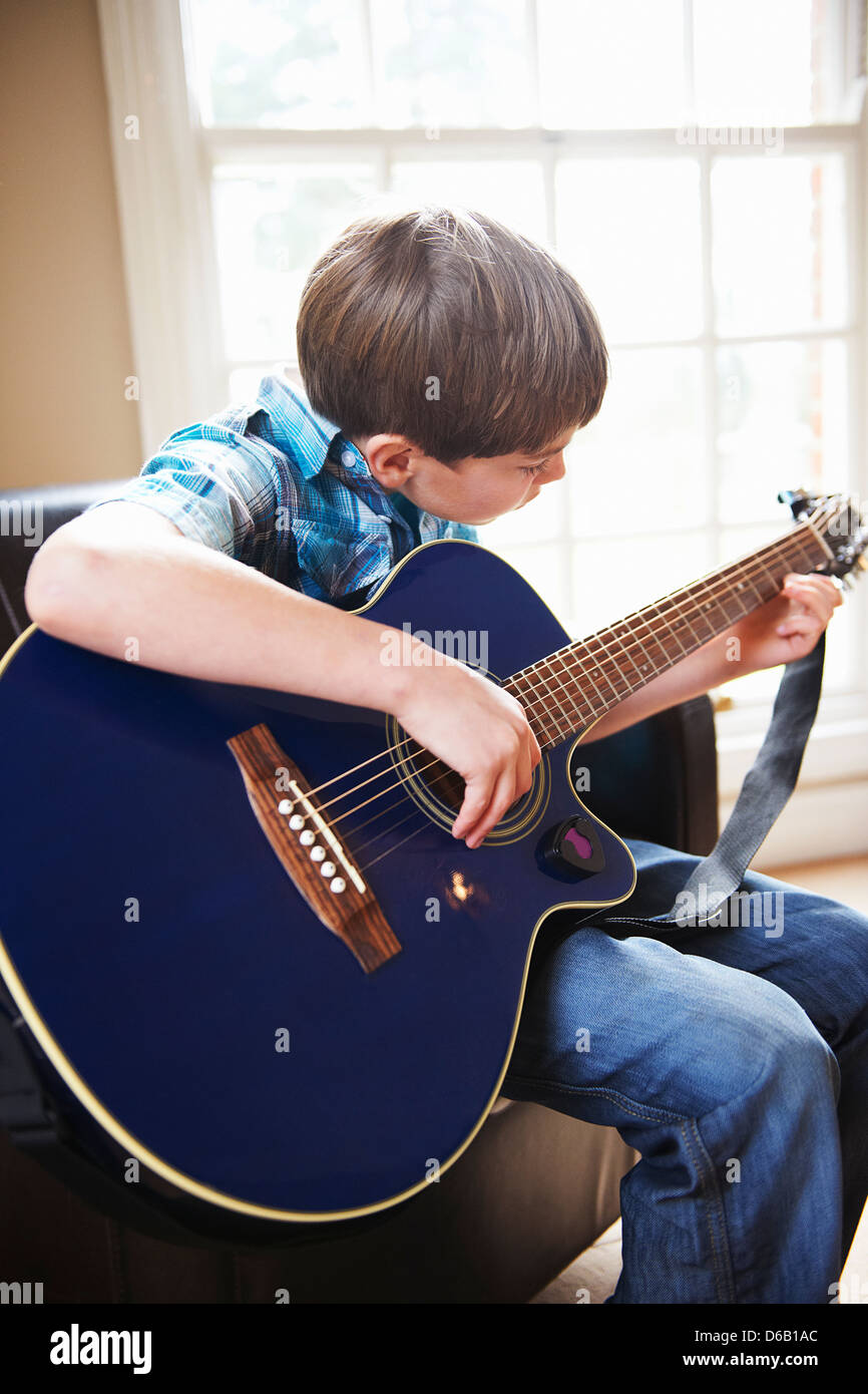 Junge Gitarre spielen auf sofa Stockfoto