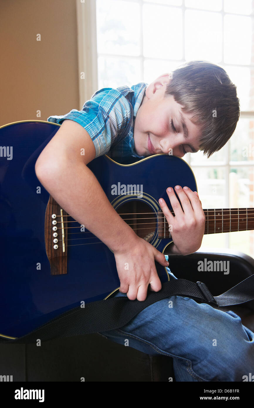 Lächelnde junge umarmt Gitarre Stockfoto
