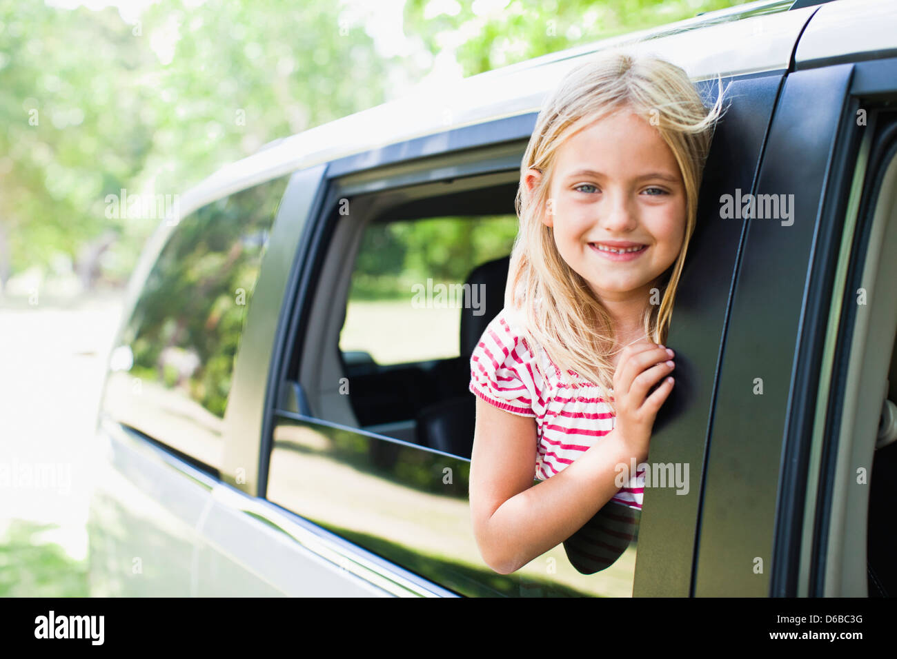Lächelndes Mädchen stehend im Autofenster Stockfoto