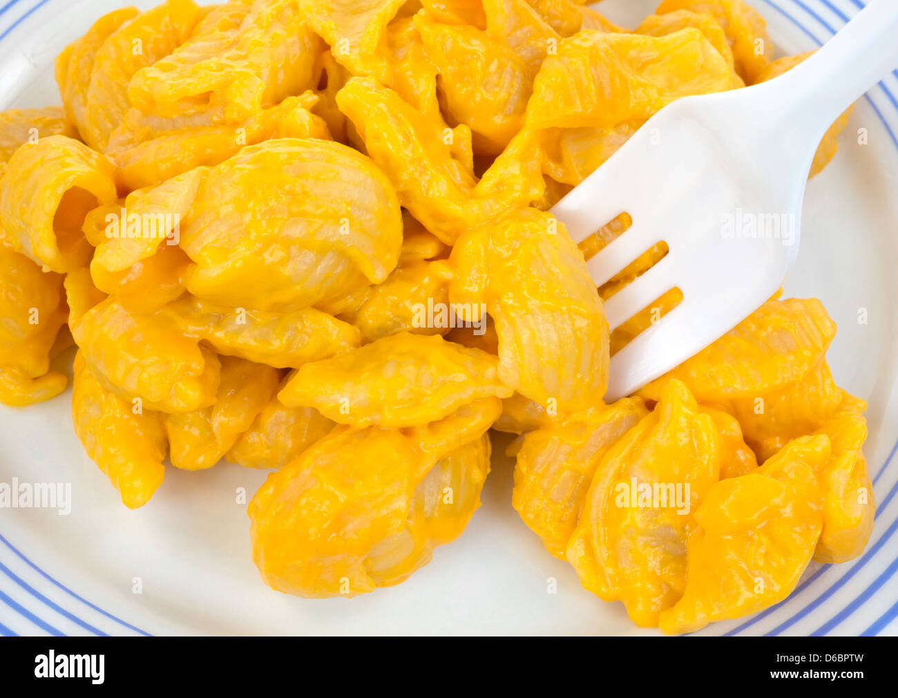 Ganz in der Nähe Blick auf eine kleine Portion Nudeln Muscheln mit Käse-Sauce auf einem Teller mit einer Gabel aus Kunststoff. Stockfoto