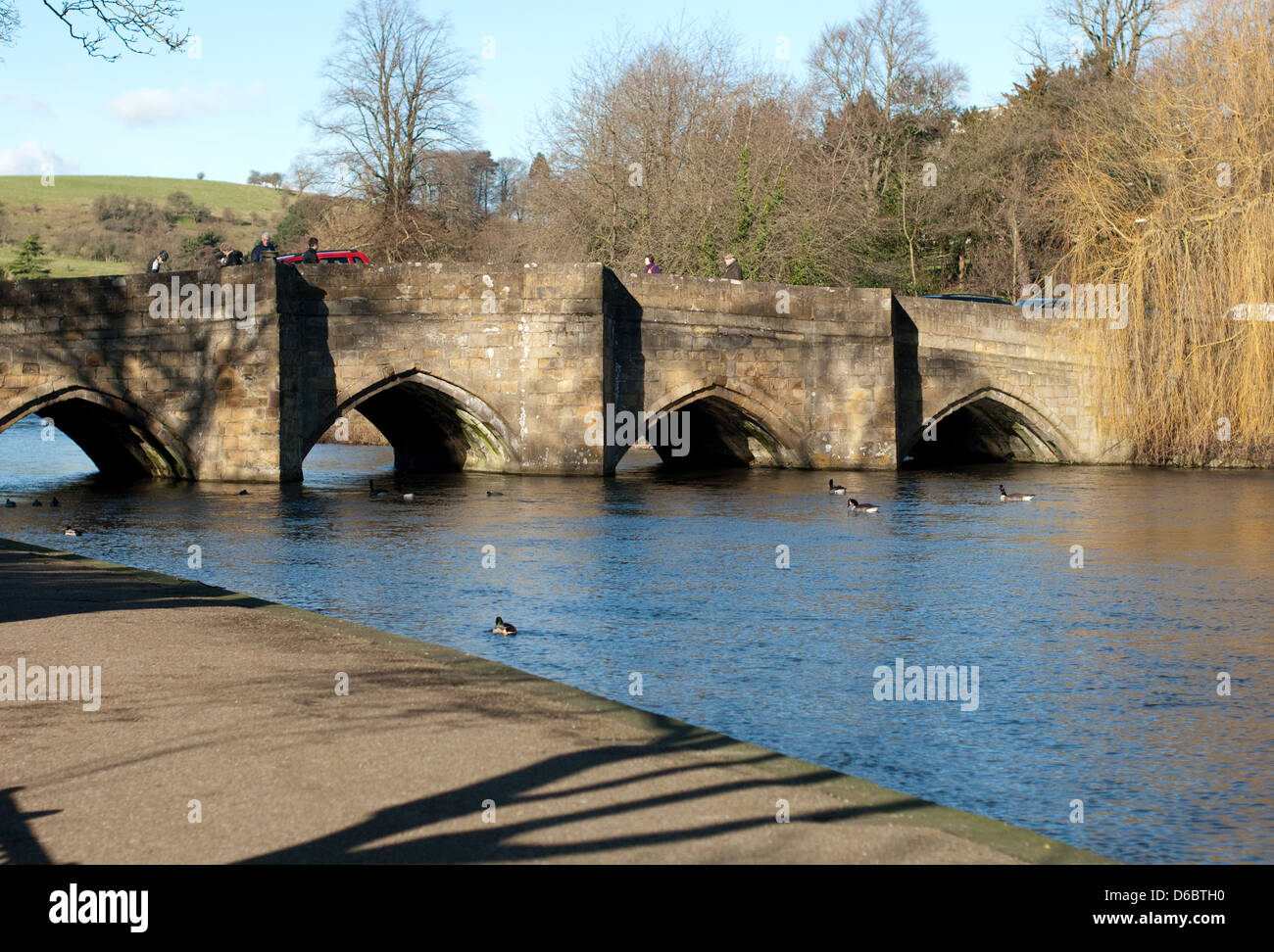 Mit Blick auf die steinerne Brücke über den Fluss Wye in Bakewell zeigt Menschen und Tops von Autos wie sie Crossover der Brücke. Stockfoto
